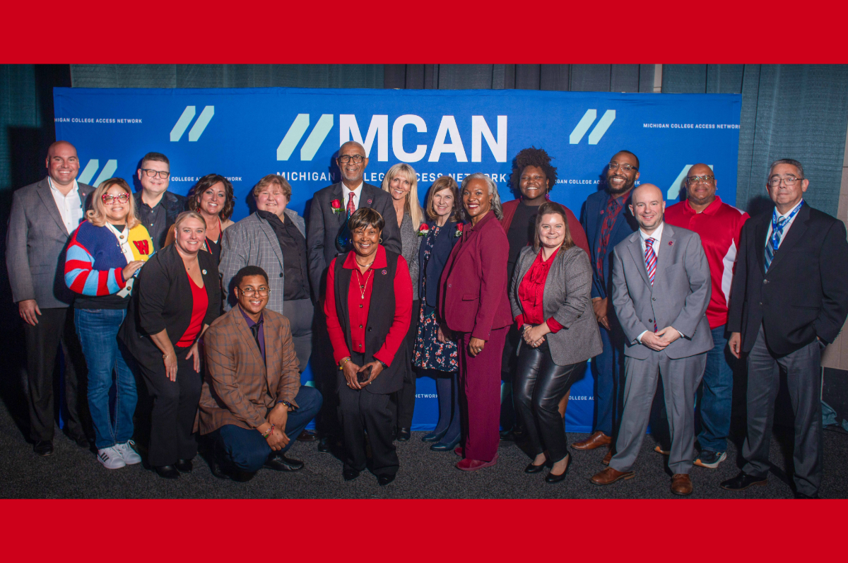 group of people standing in front of back drop that reads MCAN
